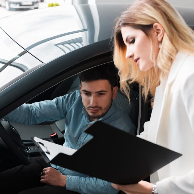 Car saleswoman shows documents for male client