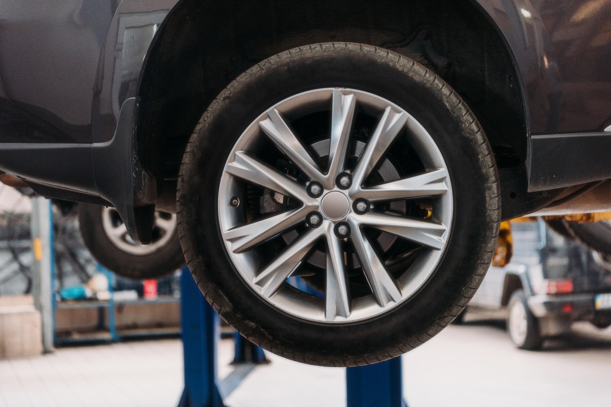 A closeup of a wheel on a lifted up car at a repair workshop.